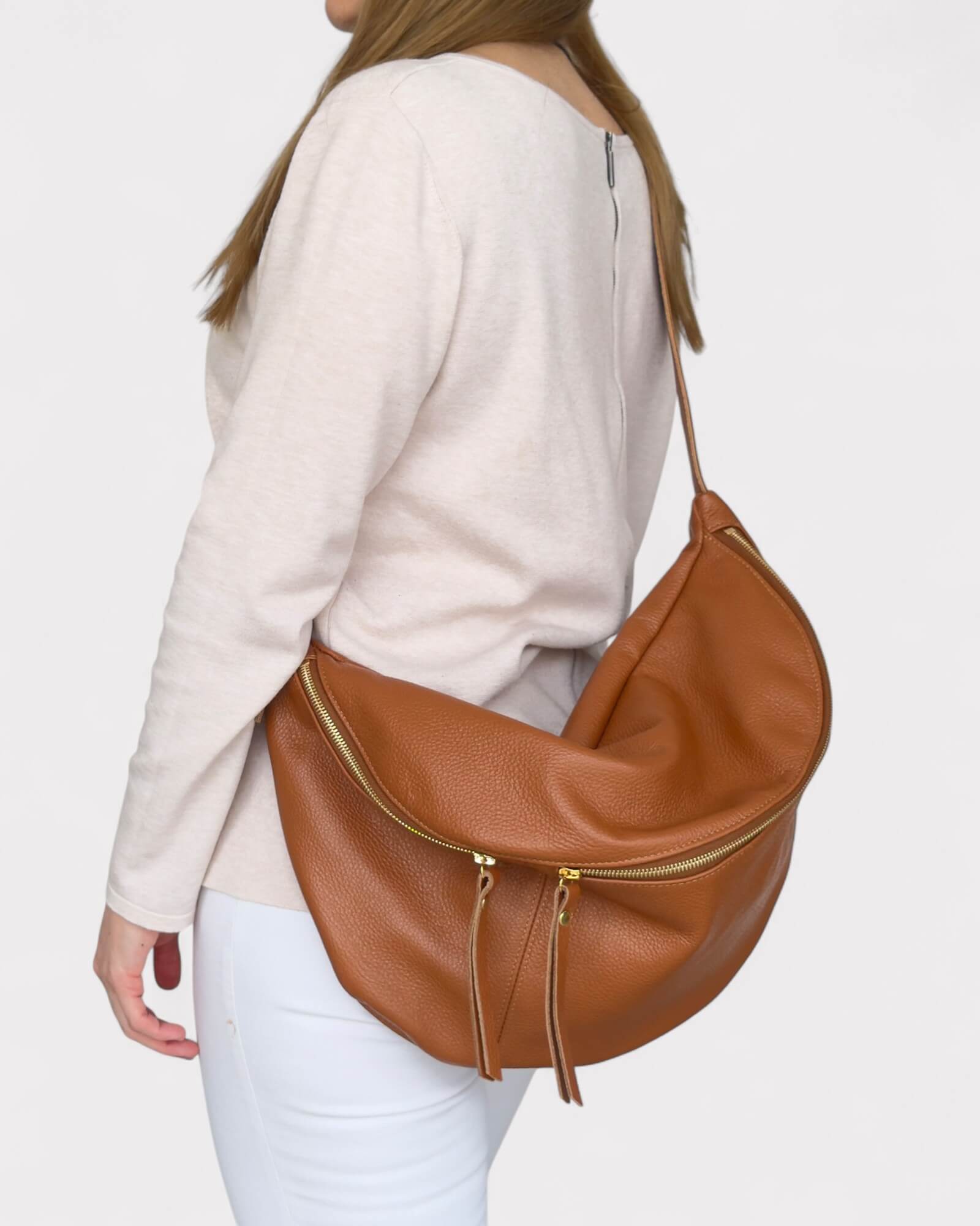 Person wearing a tan leather handbag on a plain background