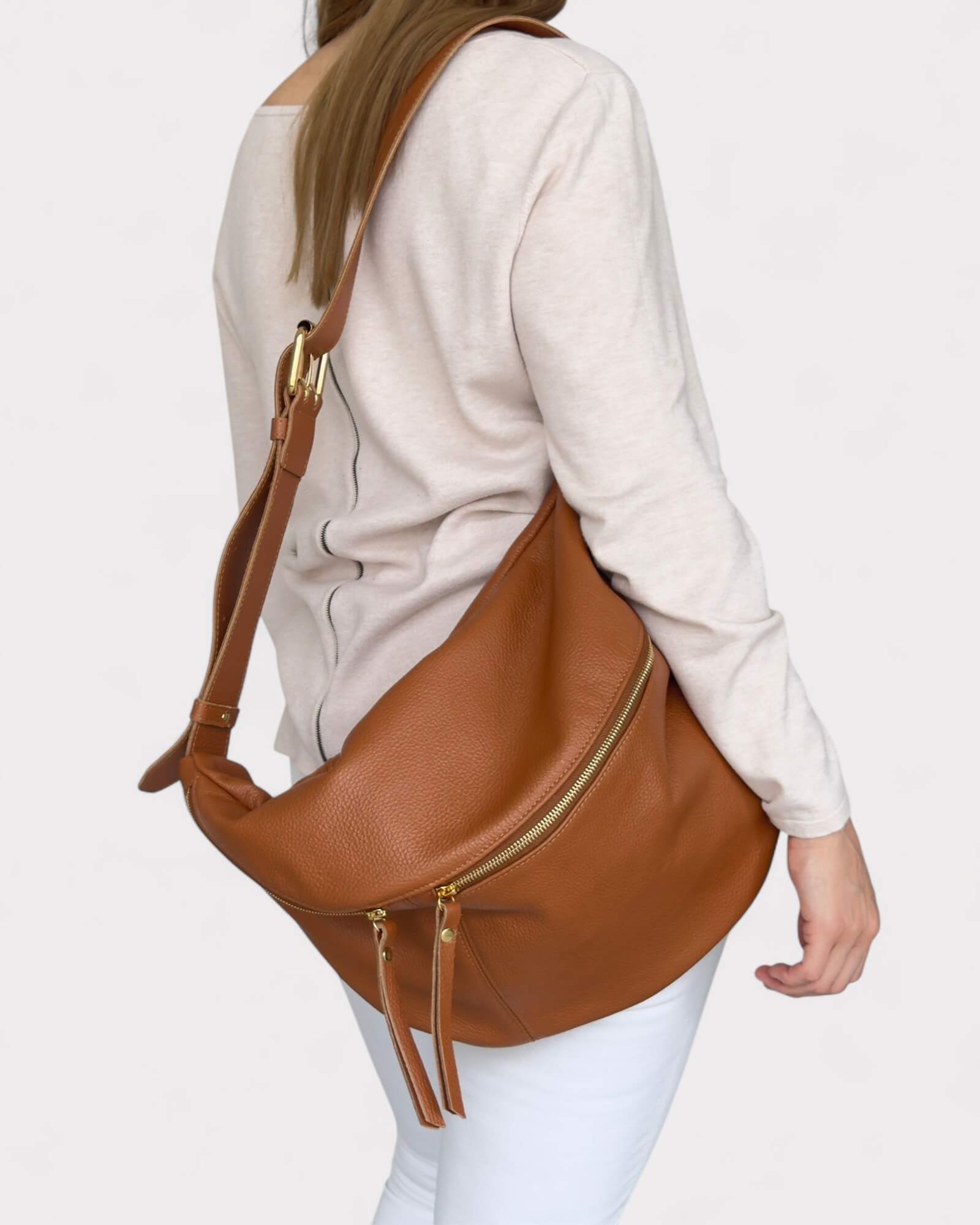 Tan leather fanny pack worn by a person on a light gray background