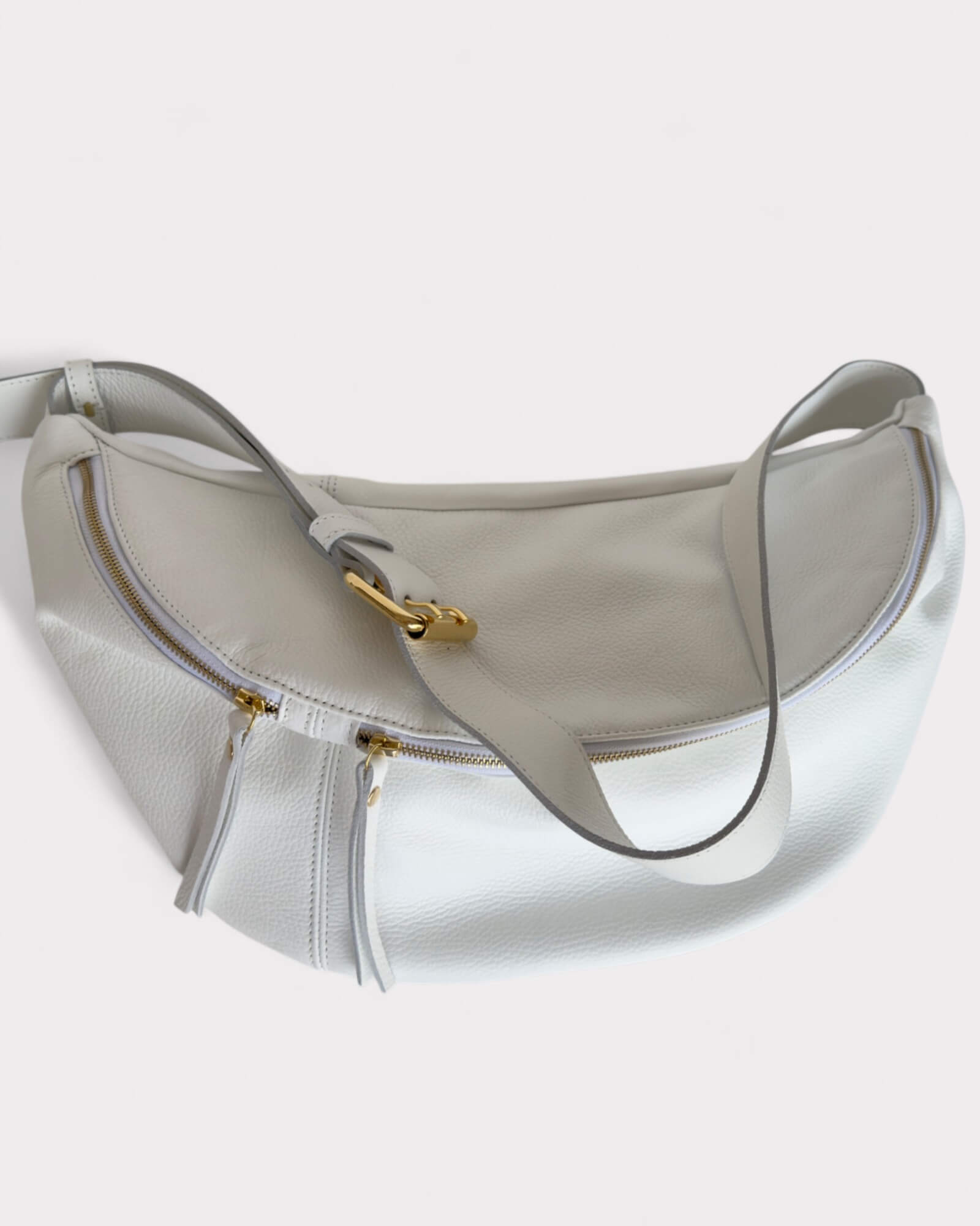 White handbag with gold accents on a light gray background