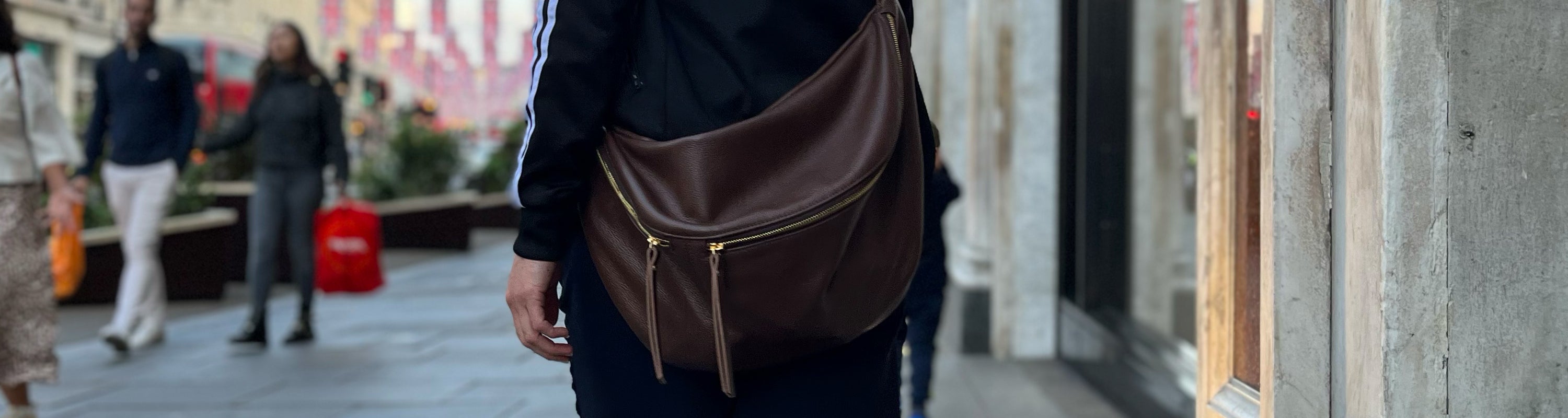 Person wearing a brown crossbody bag in an urban setting