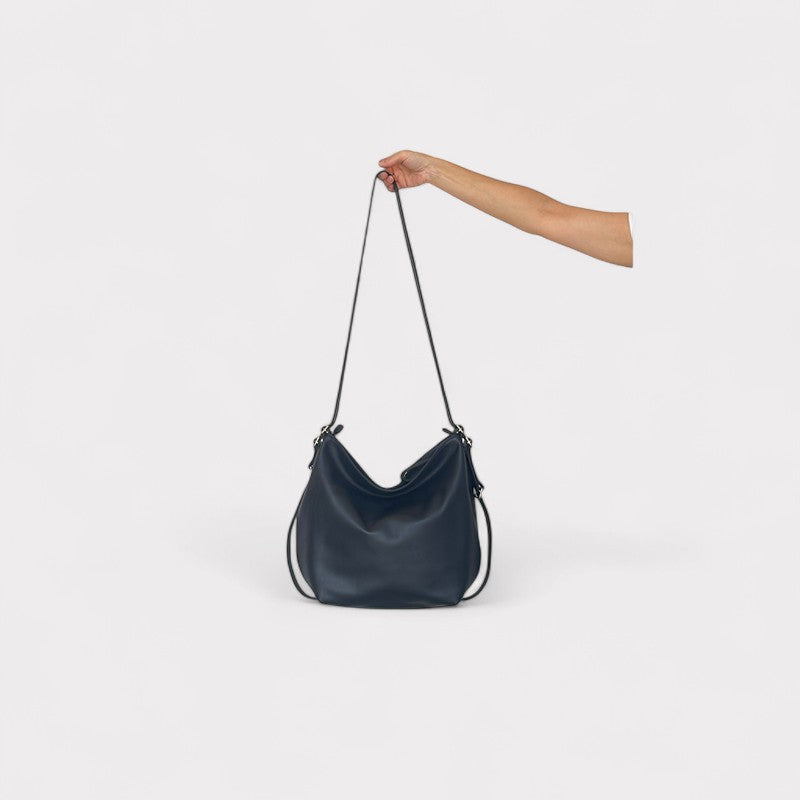 Black handbag held by a hand against a white background
