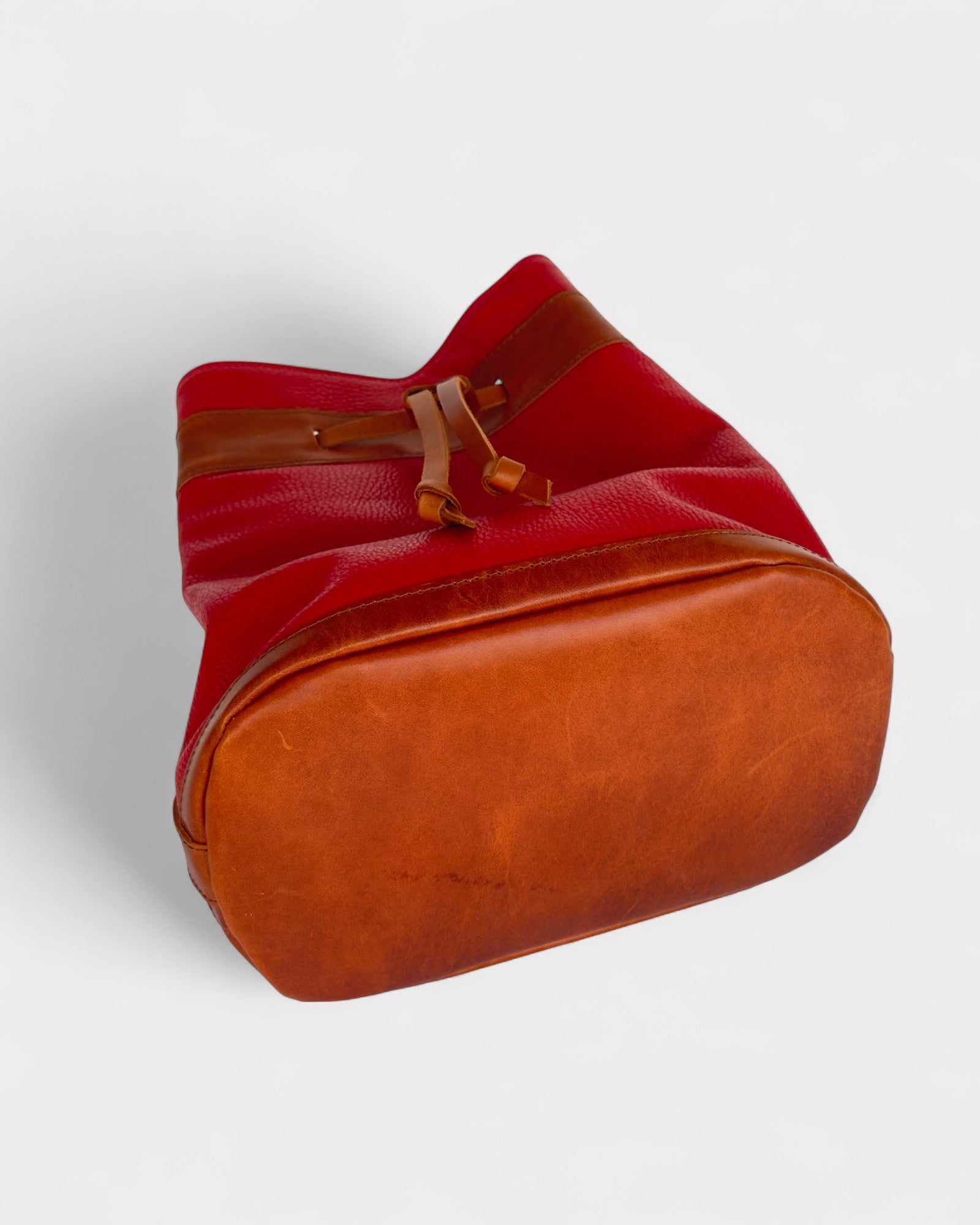 Red and brown bucket leather bag on a light gray background