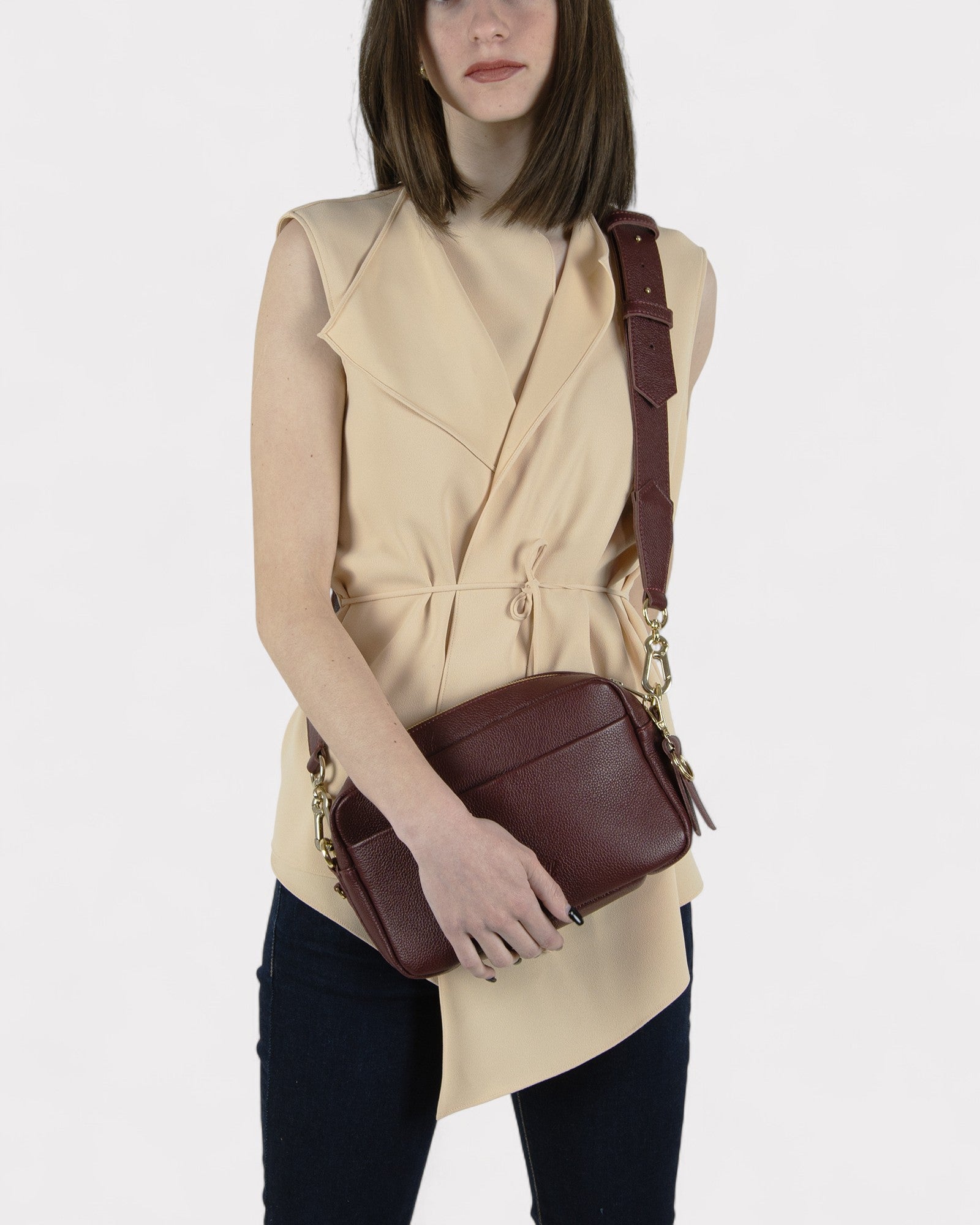 Woman holding a burgundy leather bag against a white background