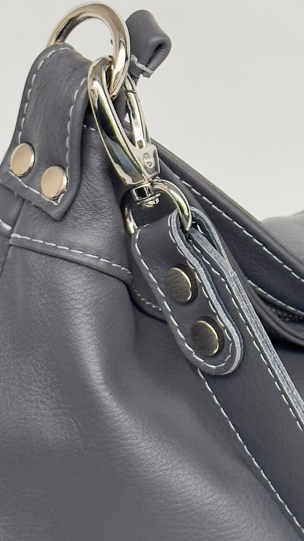 Close-up of a gray leather bag with a metal clasp on a light gray background