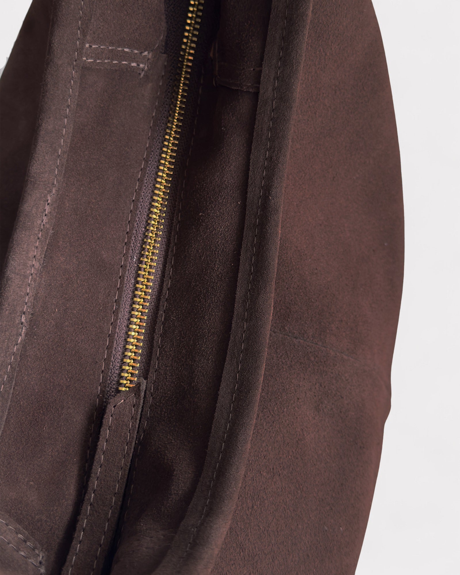 Close-up of a brown leather bag with a gold zipper on a white background