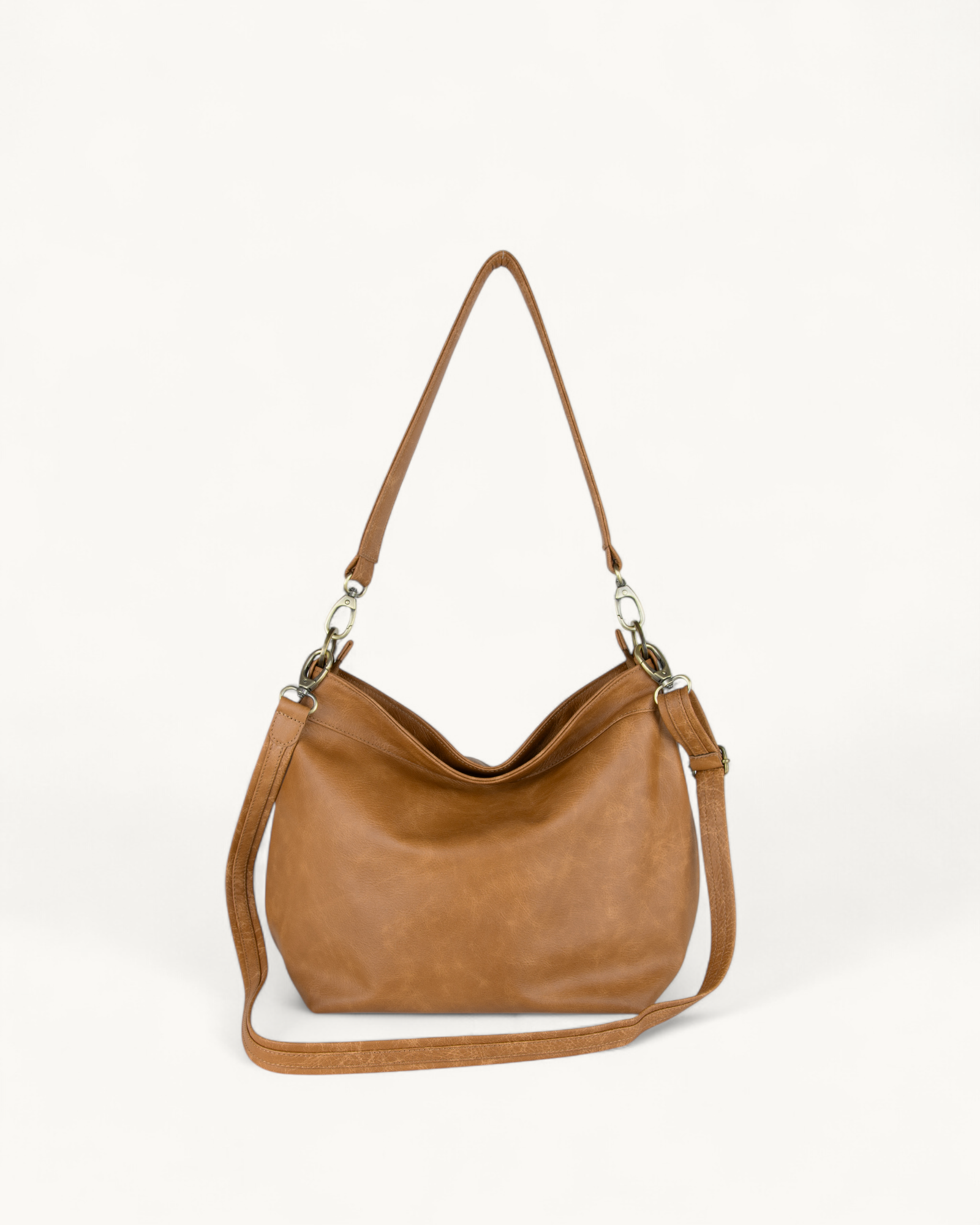 Distressed Tan leather handbag with a shoulder strap on a white background