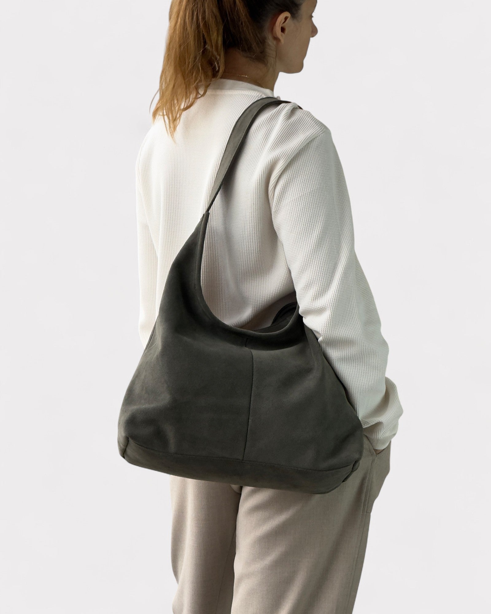 Person wearing a green shoulder bag on a plain background