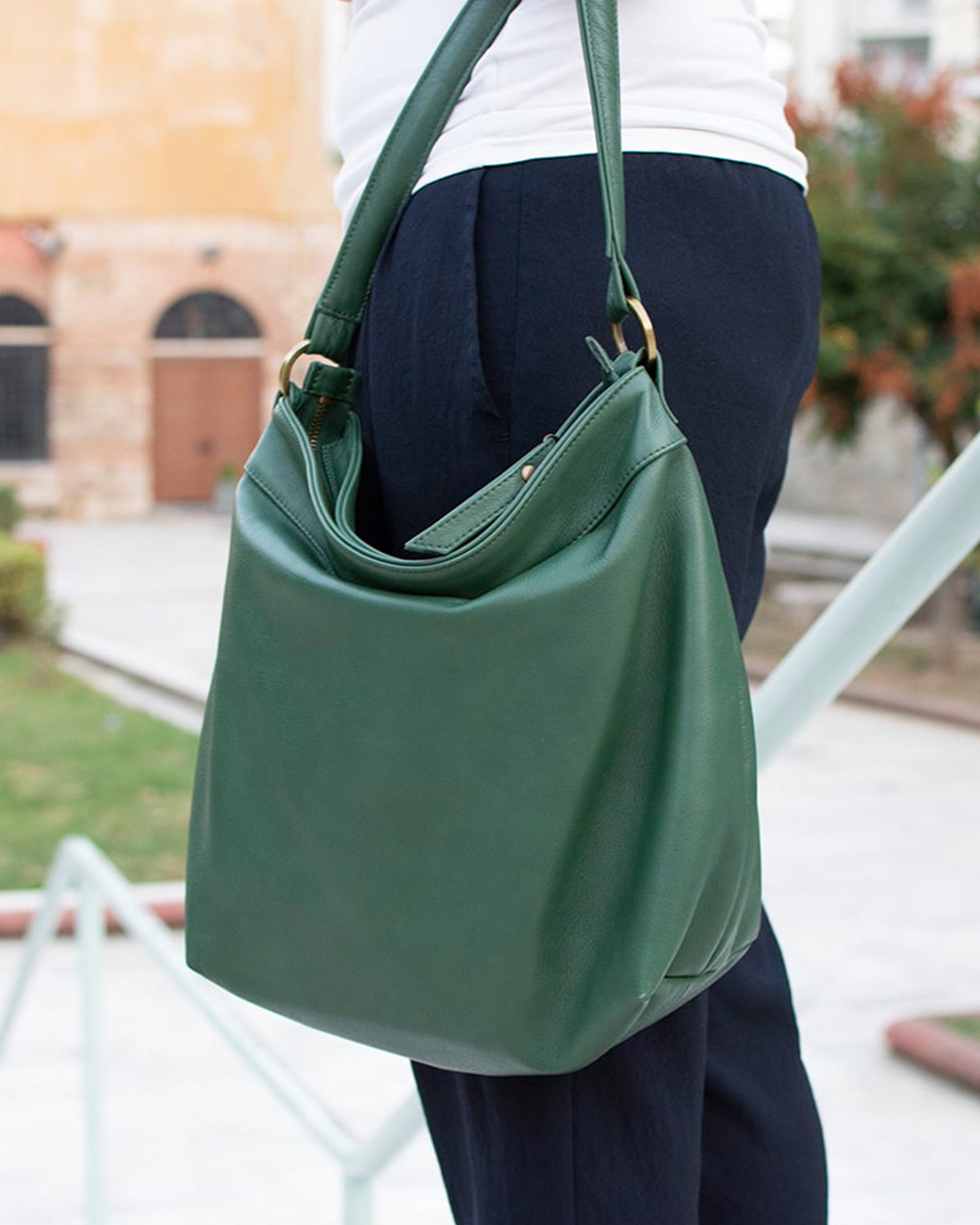 Person holding a green handbag outdoors