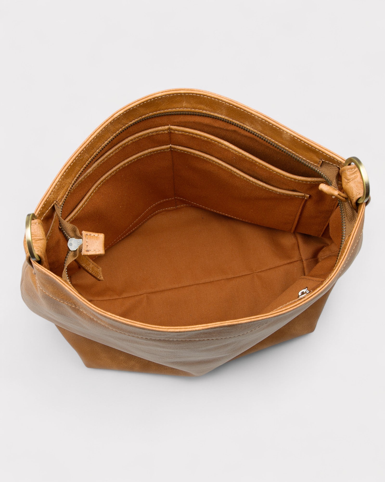 Tan distressed leather handbag with open top on a light gray background