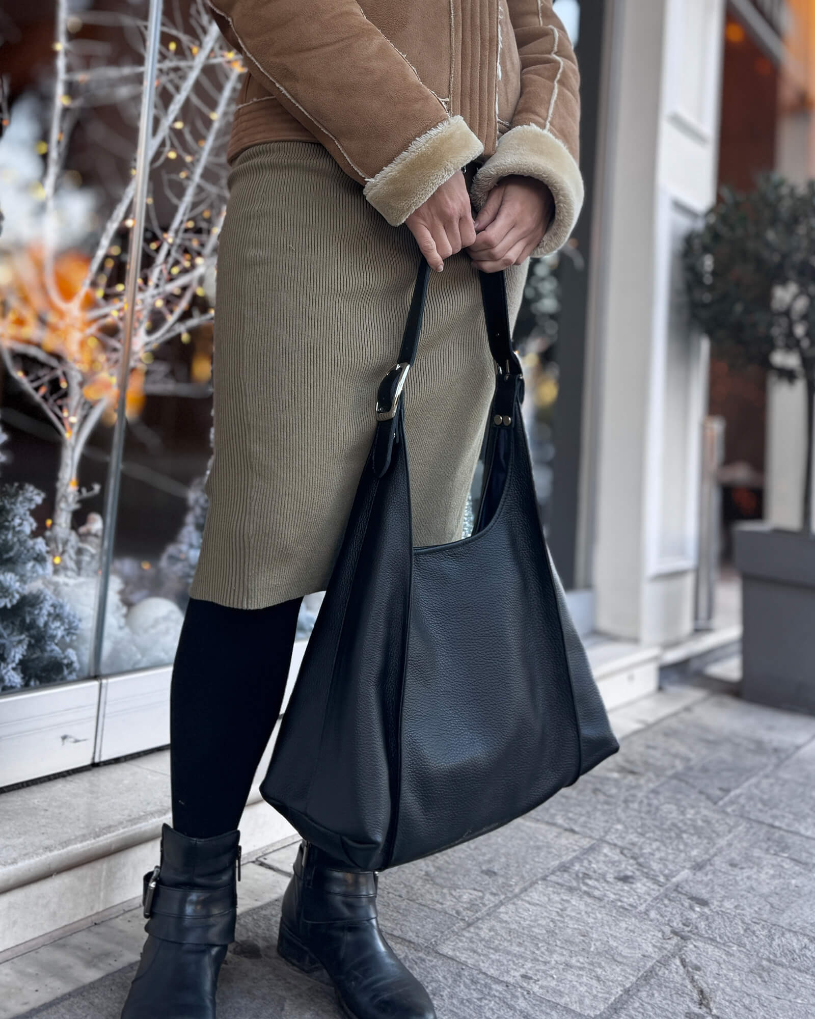 Person holding a black handbag in an urban setting