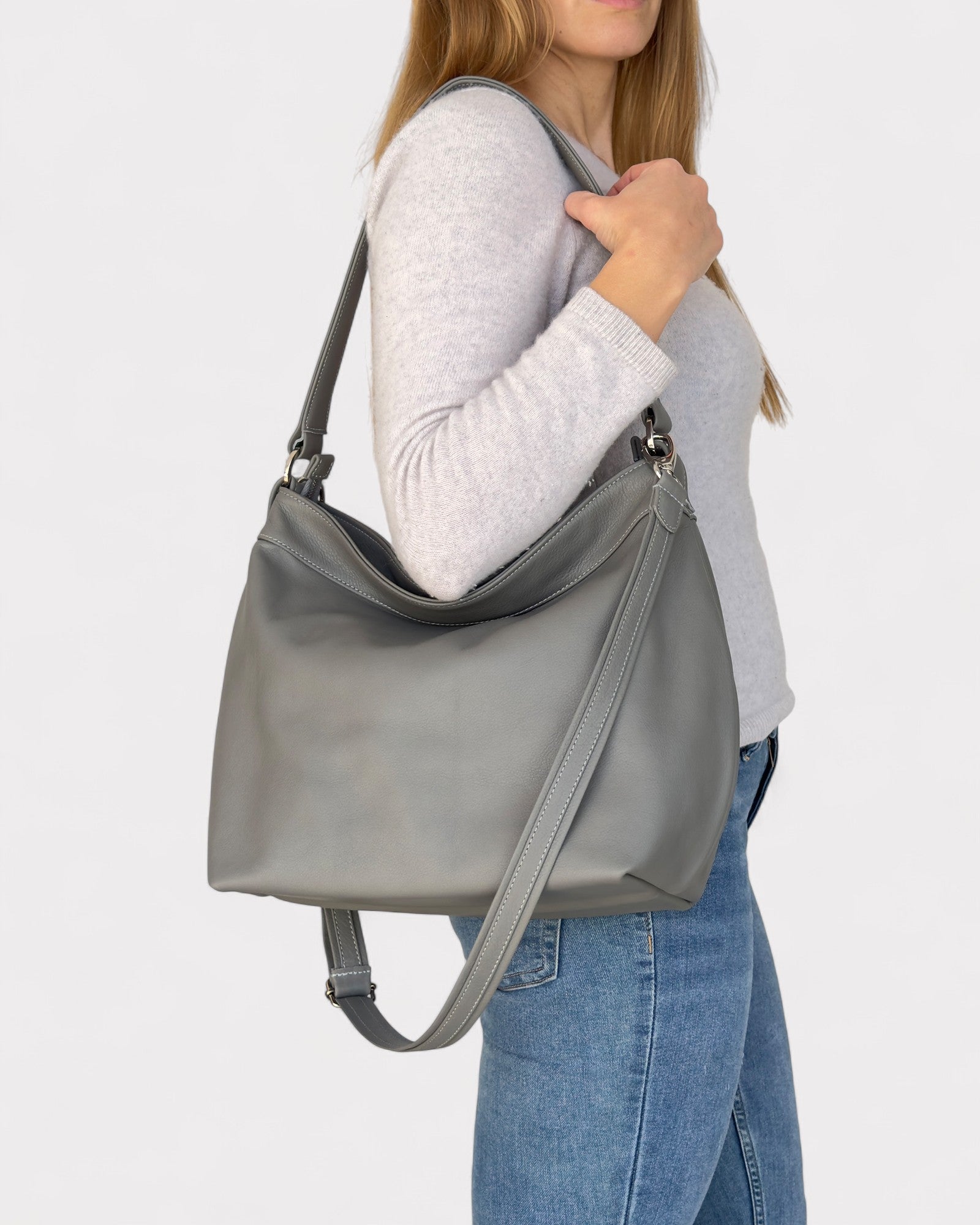 Person holding a gray shoulder bag against a white background