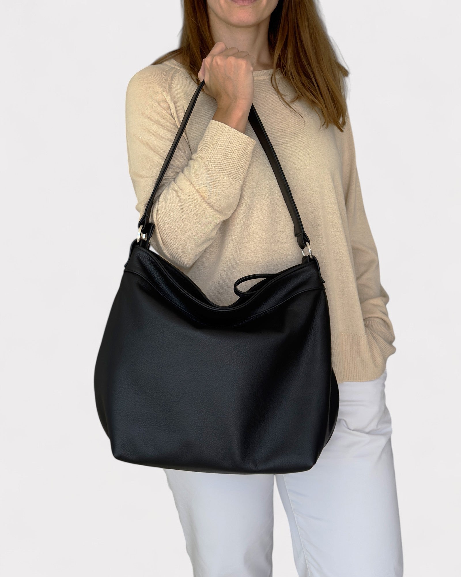 Person holding a black shoulder bag against a white background