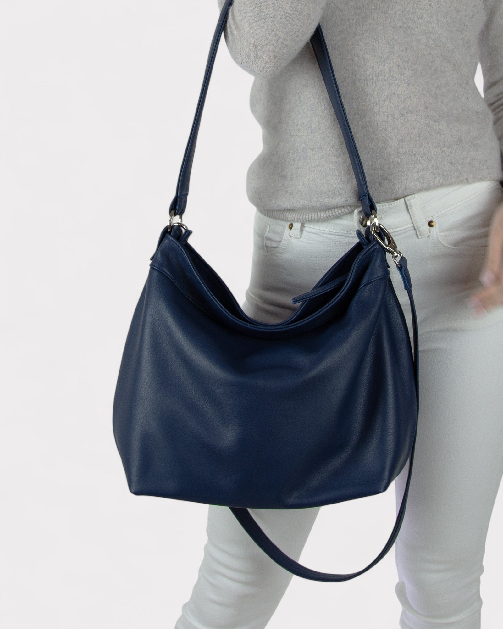 Navy blue handbag worn by a person on a light gray background