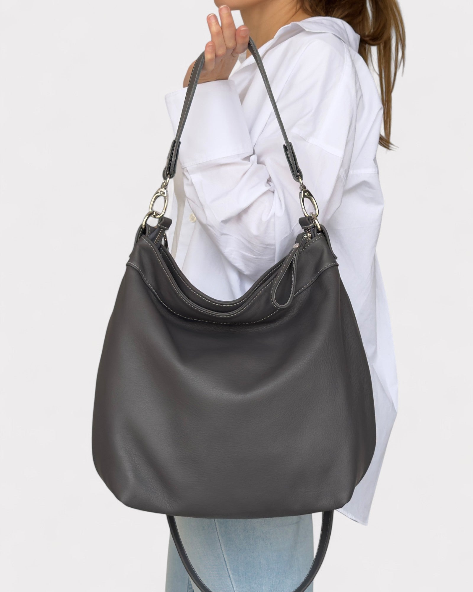 Person wearing a gray shoulder bag on a plain background