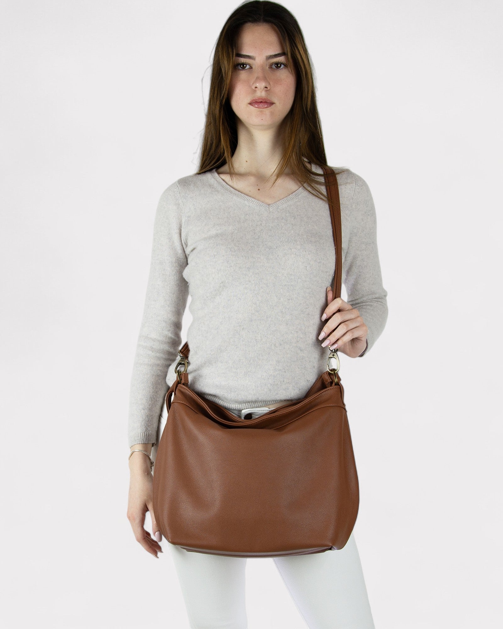 Woman holding a Cognac brown leather shoulder bag against a white background