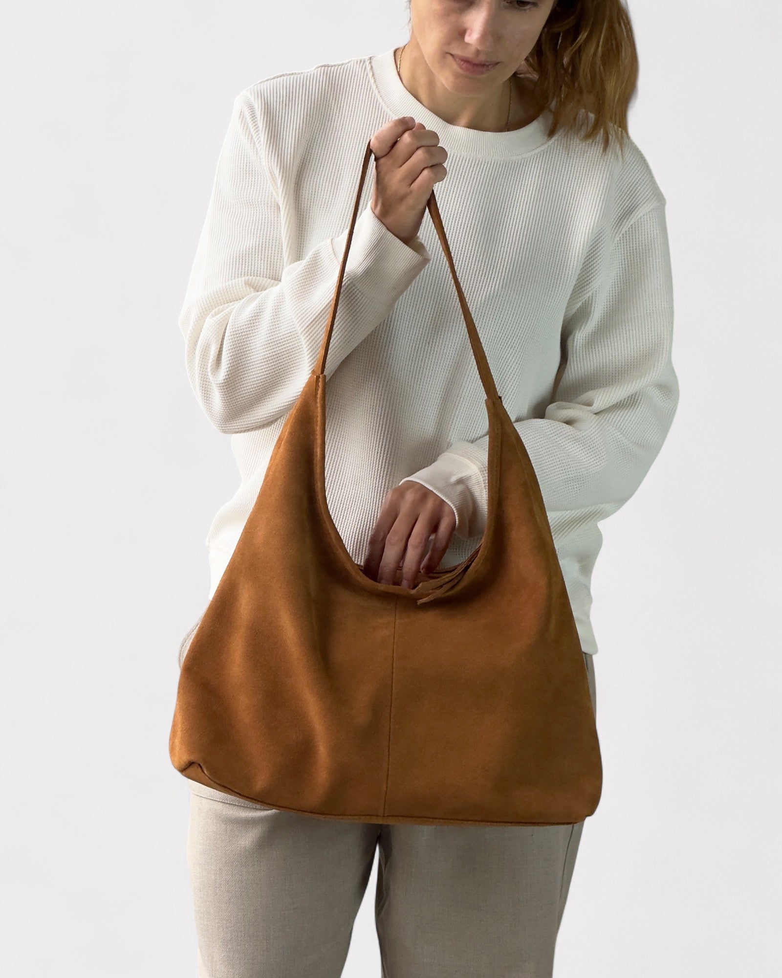 Woman holding a tan leather bag against a white background