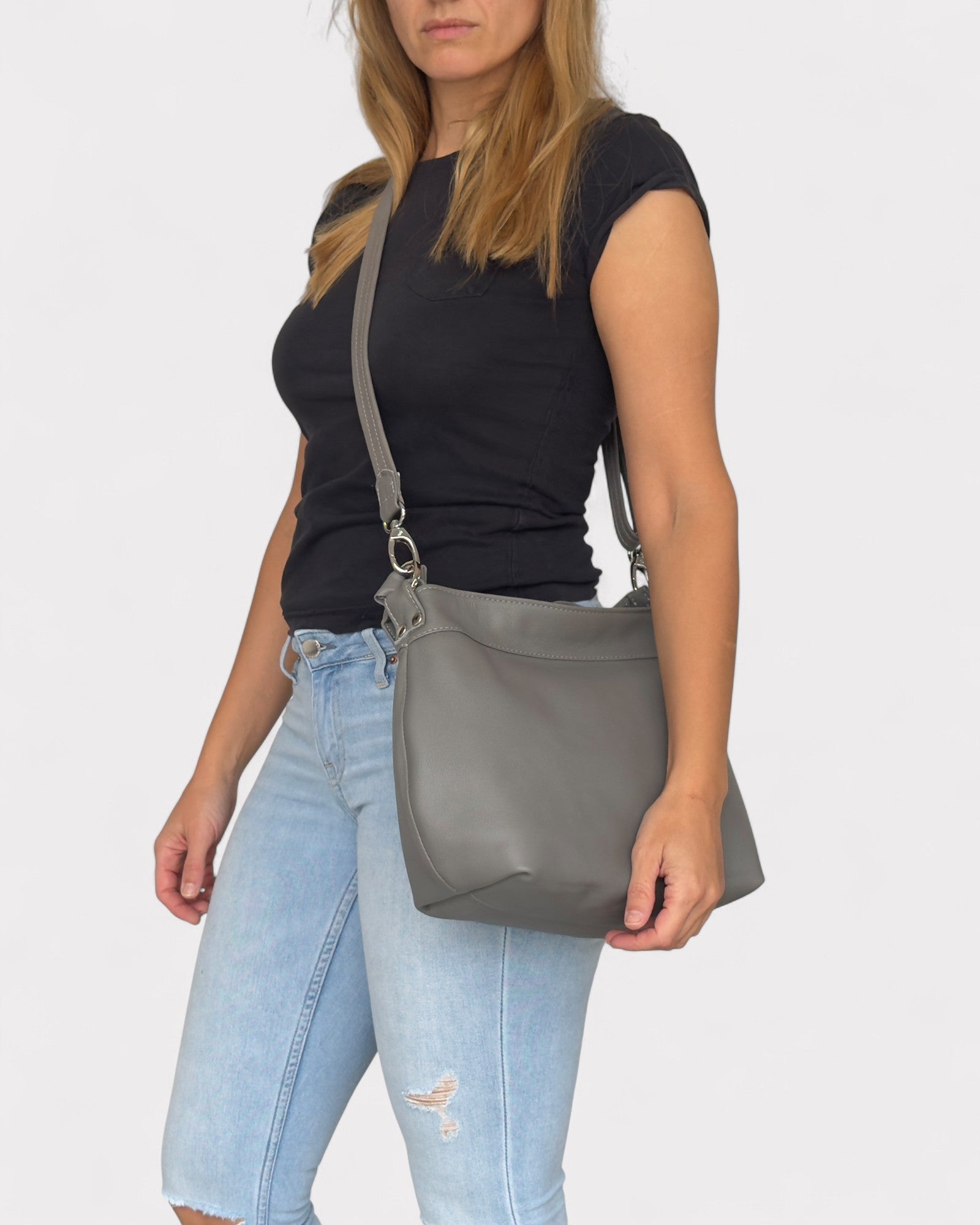 Woman carrying a gray shoulder bag against a white background