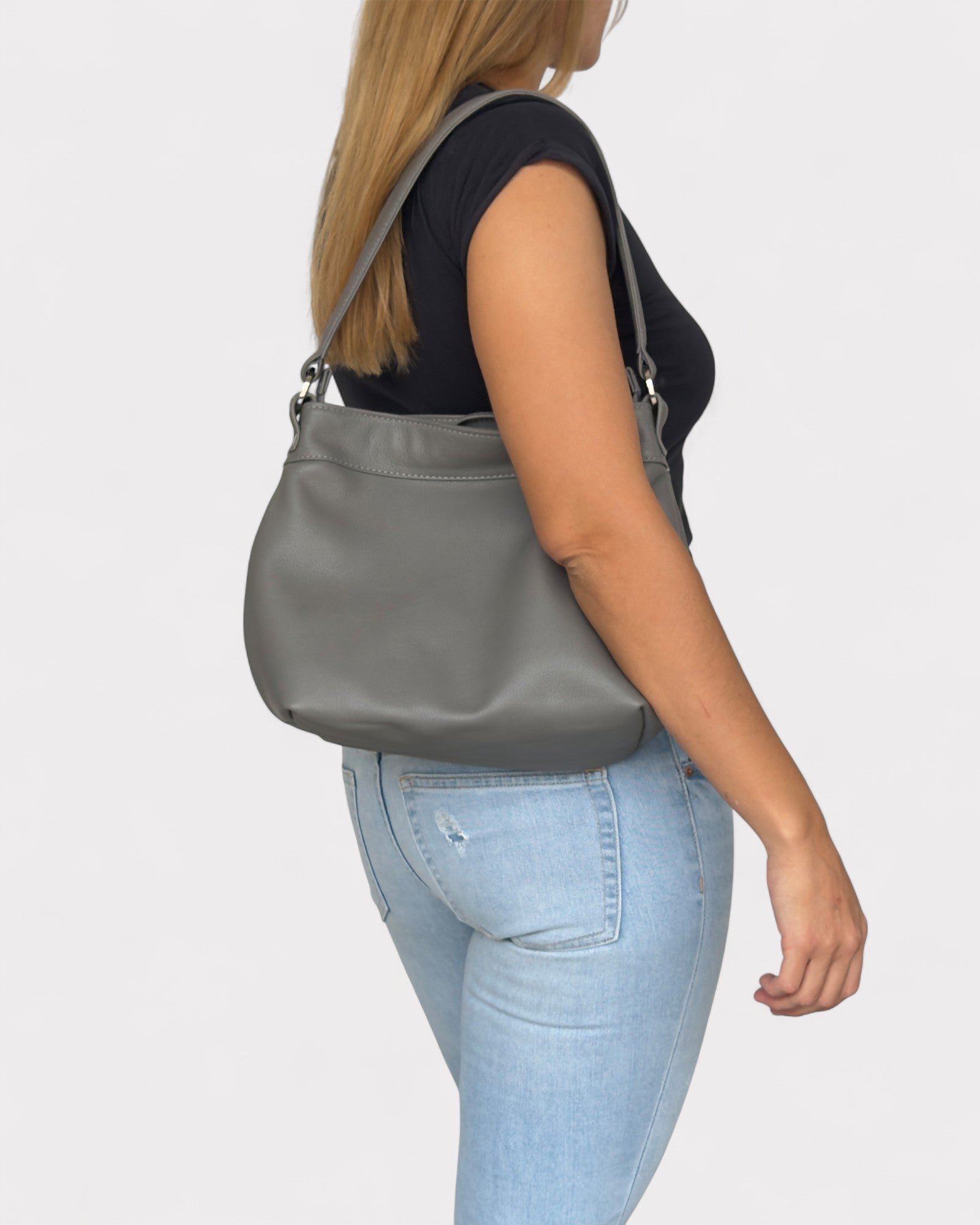 Person wearing a gray shoulder bag on a plain background