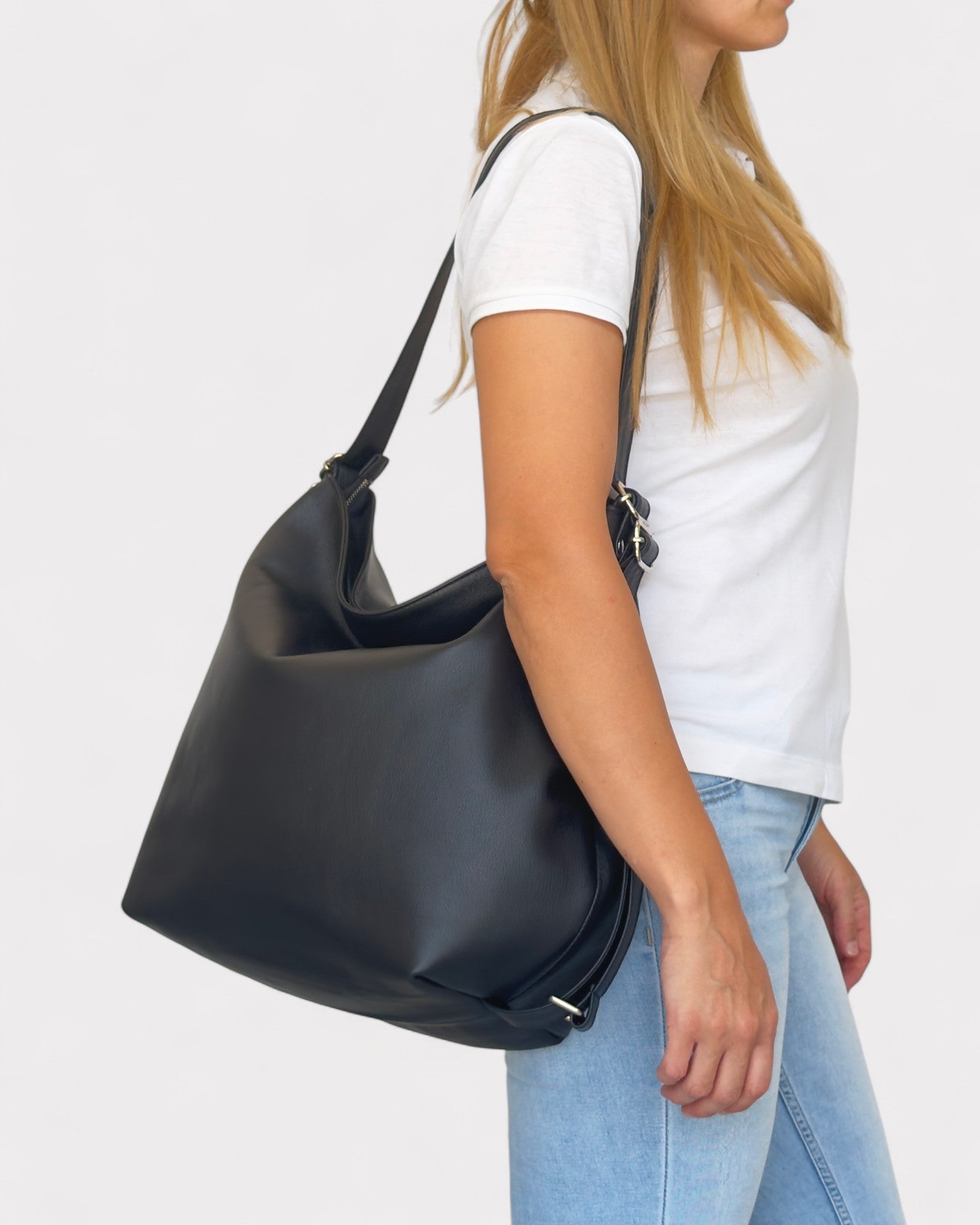 Person holding a black handbag against a white background