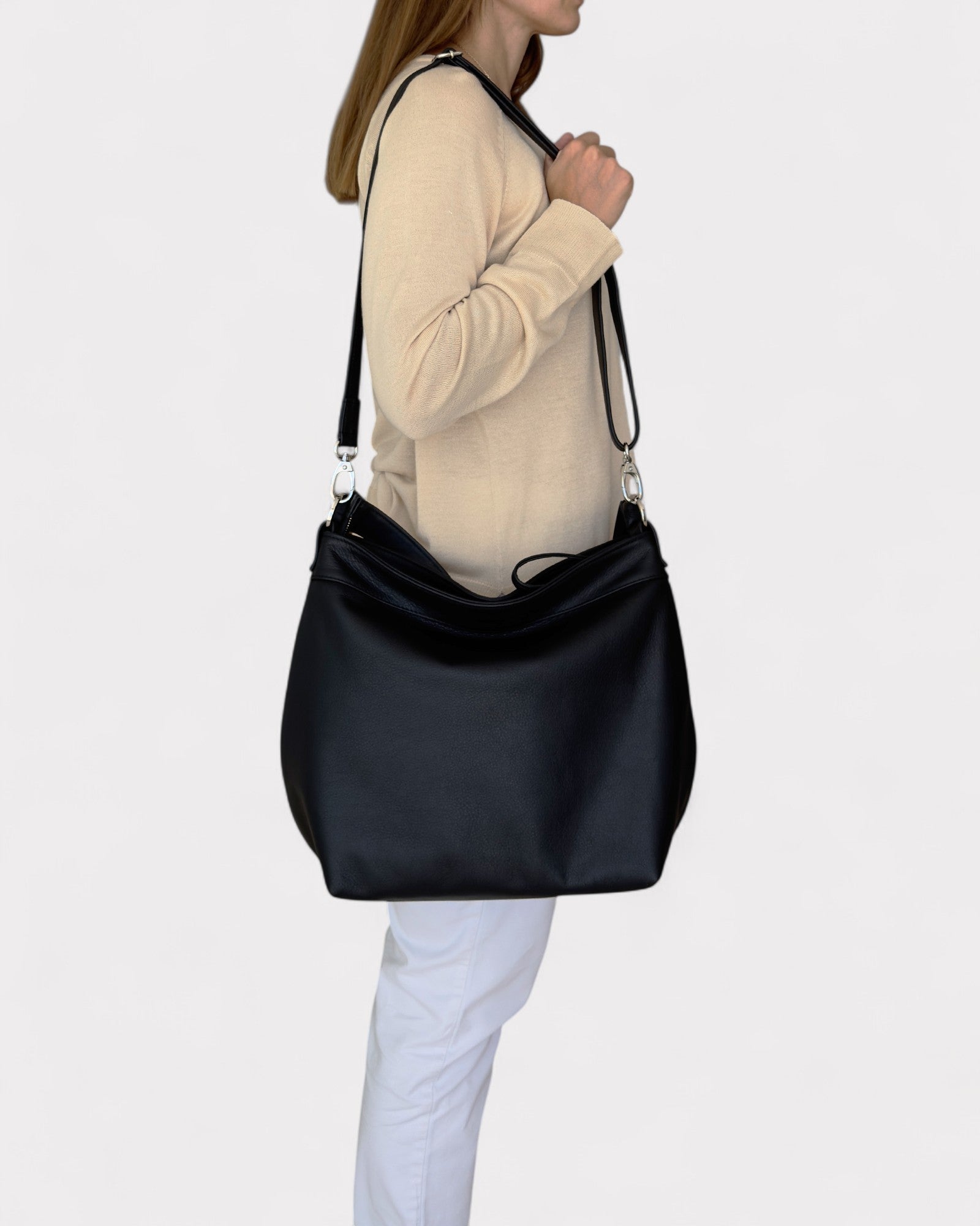 Person wearing a black shoulder bag on a plain background