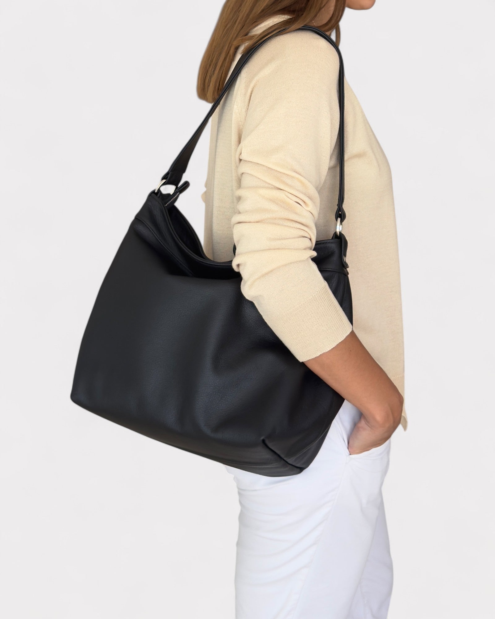Person wearing a black shoulder bag on a plain background