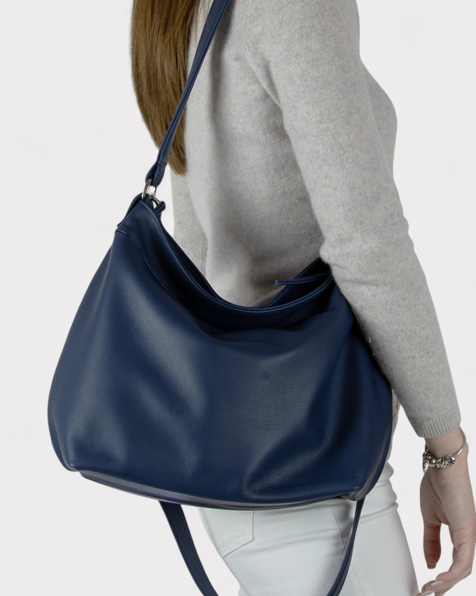 Person wearing a navy blue shoulder bag on a plain background