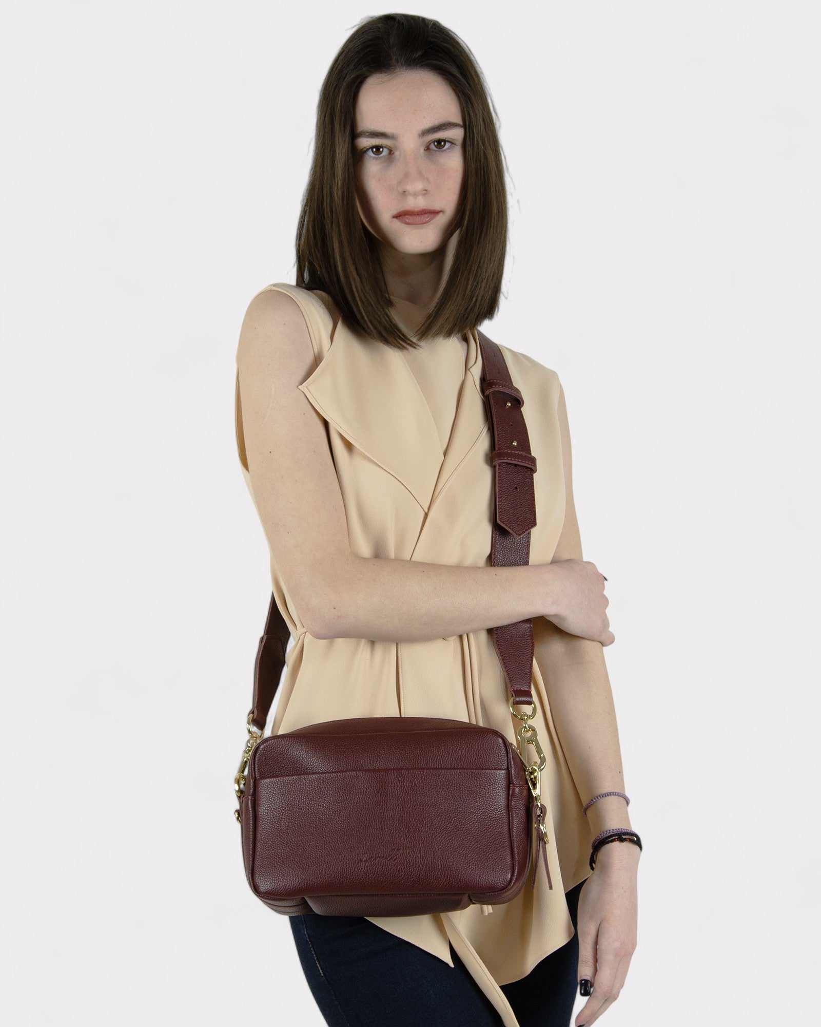 Woman holding a burgundy leather bag against a white background