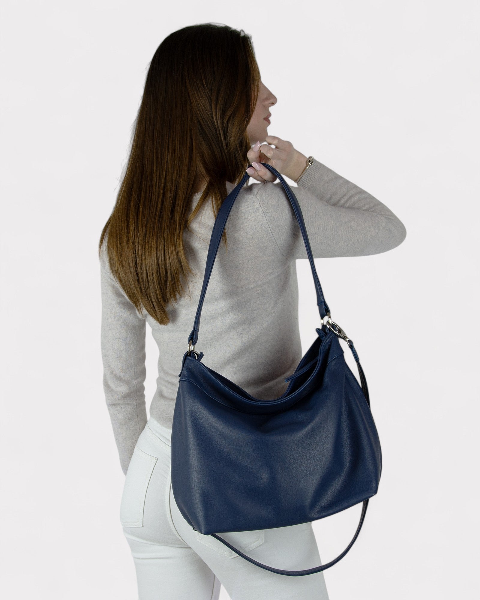Woman carrying a navy blue handbag on a plain background