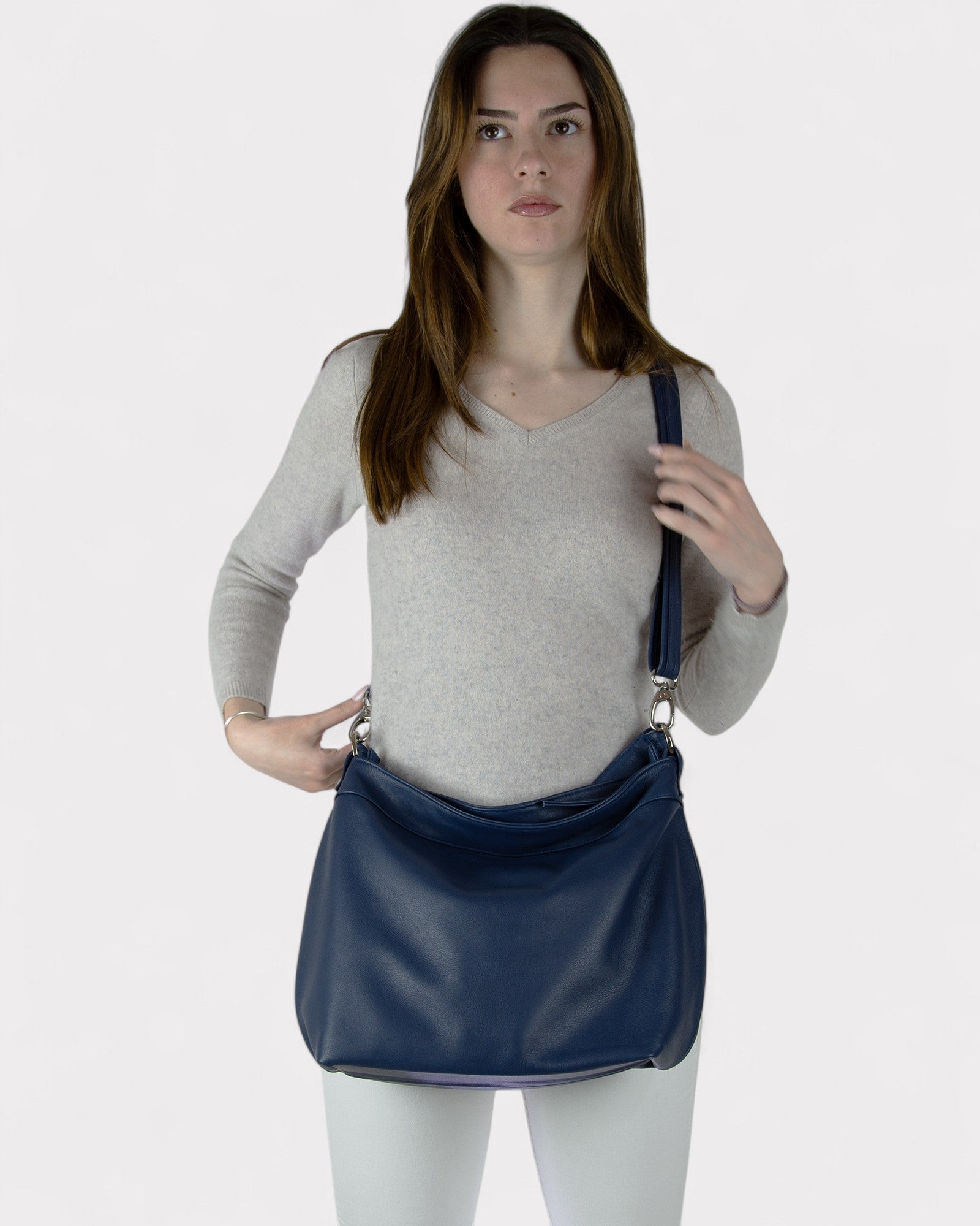 Woman holding a blue handbag against a plain background