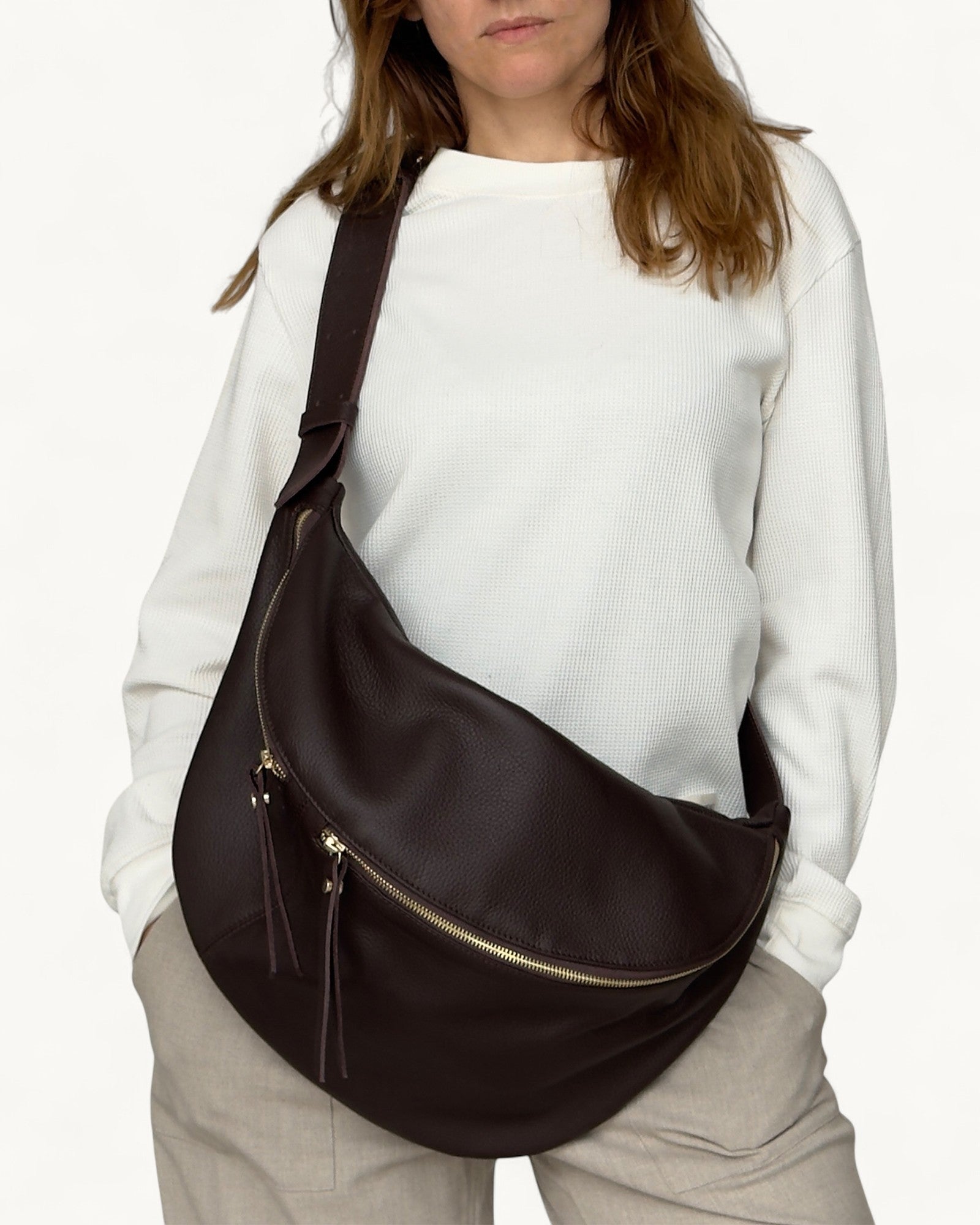 Person wearing a brown shoulder bag on a white background