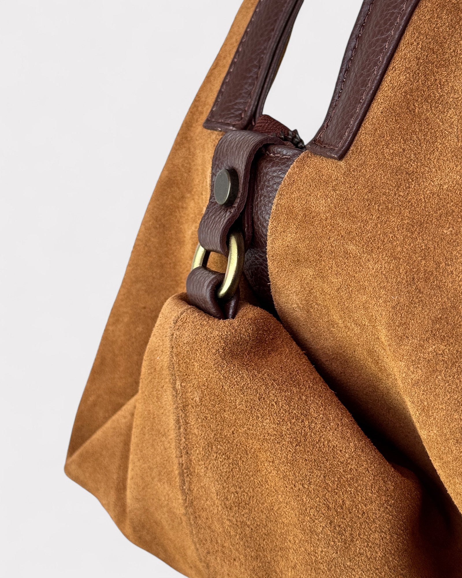 Tan leather handbag with a strap on a light gray background