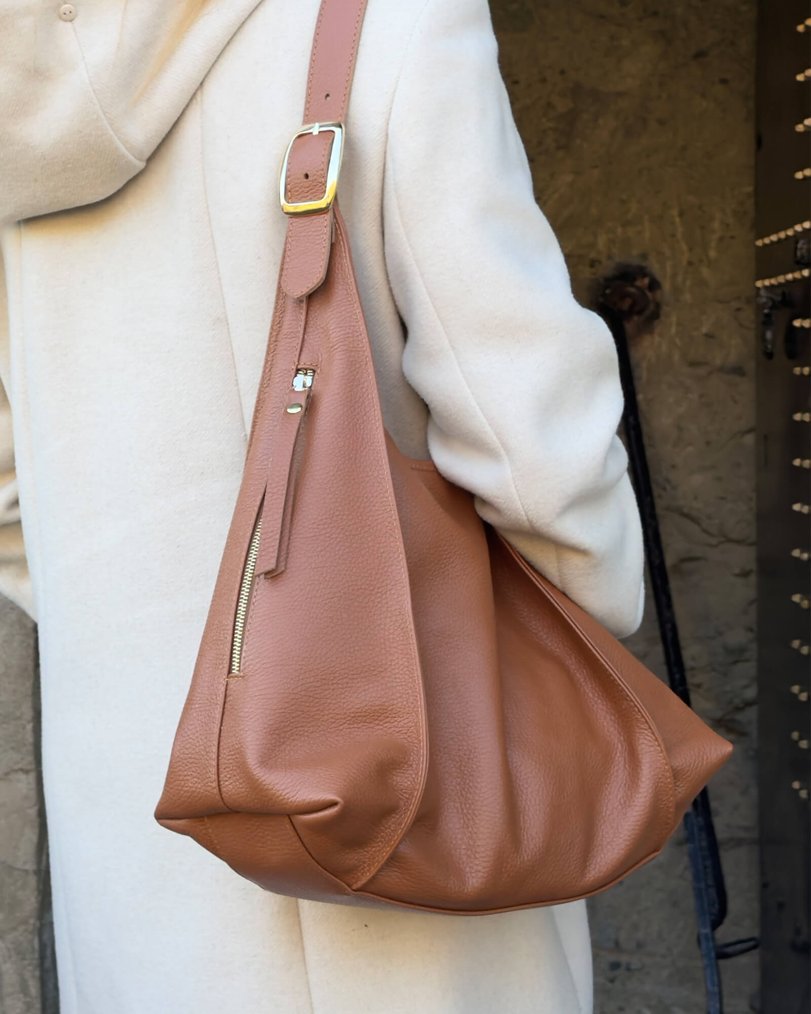 side view of model holding the tan leather shoulder bag