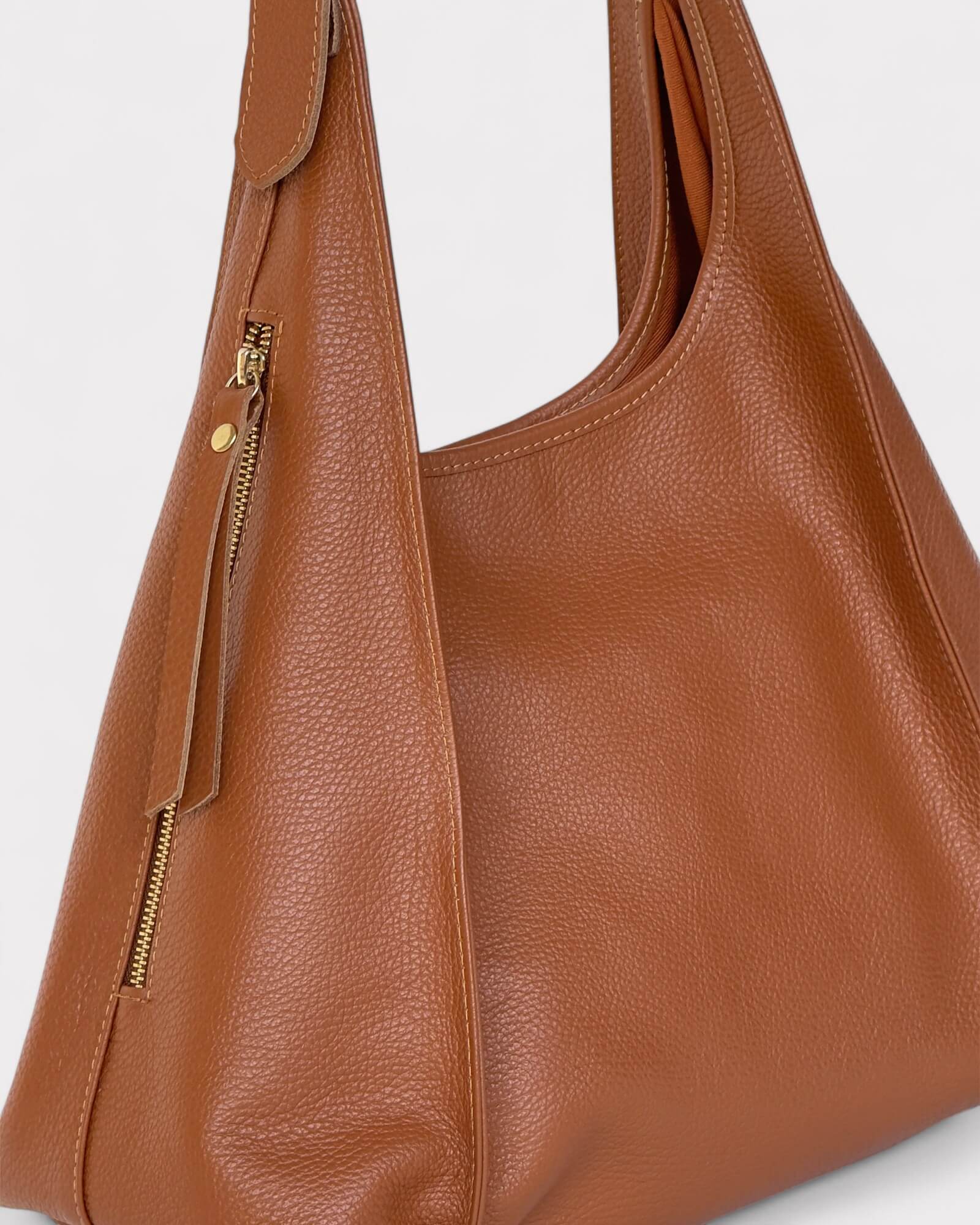 Tan leather handbag with a gold zipper on a white background