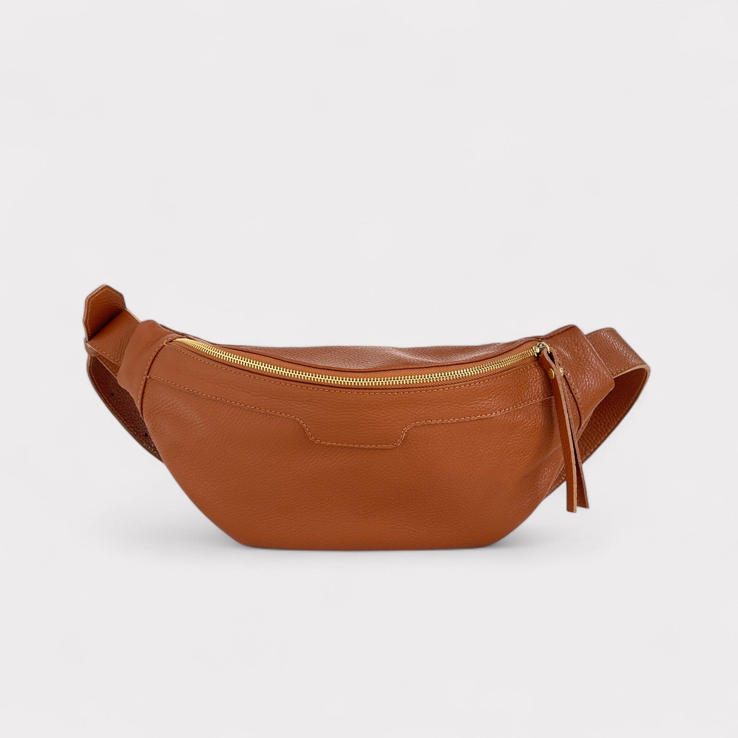 Tan leather waist bag with a gold zipper on a light gray background