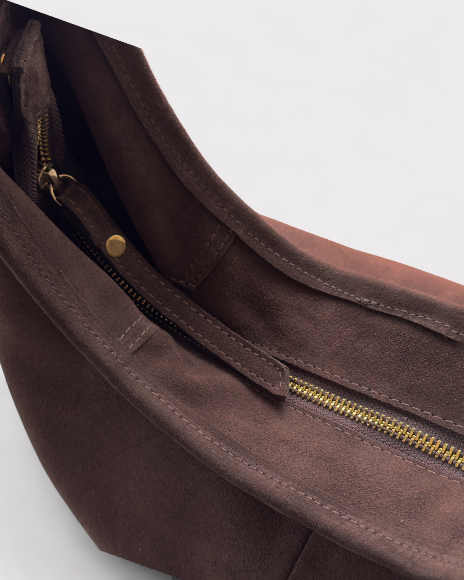 Brown suede bag with gold zipper on a light gray background