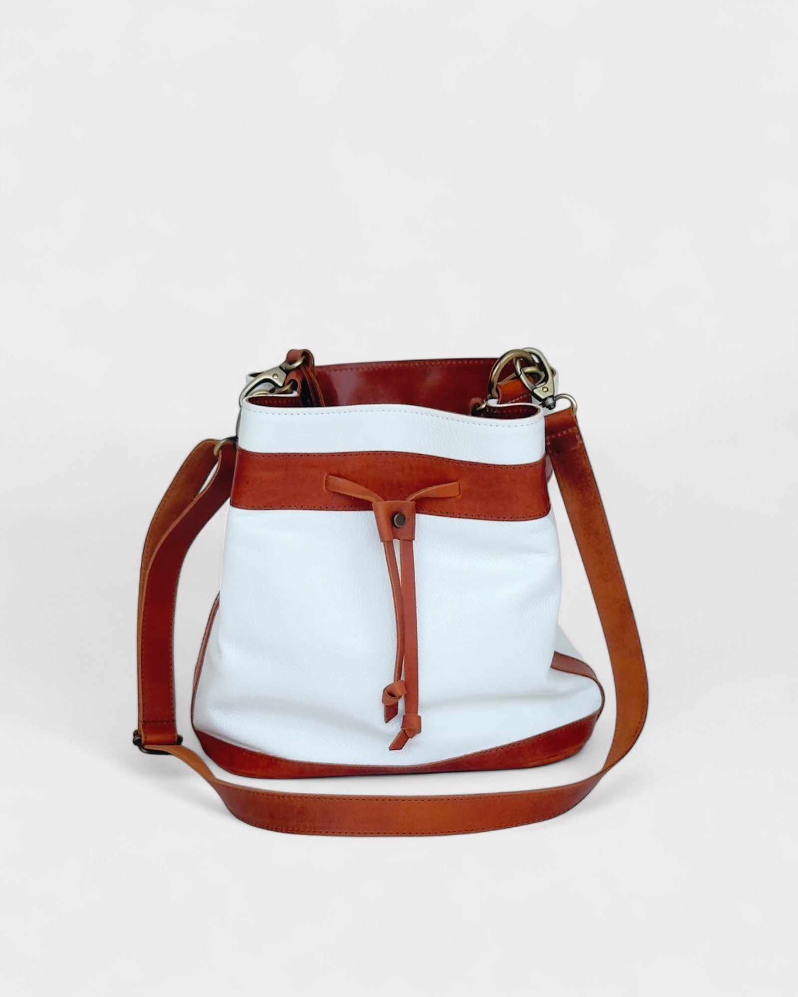 White handbag with brown leather accents on a light gray background