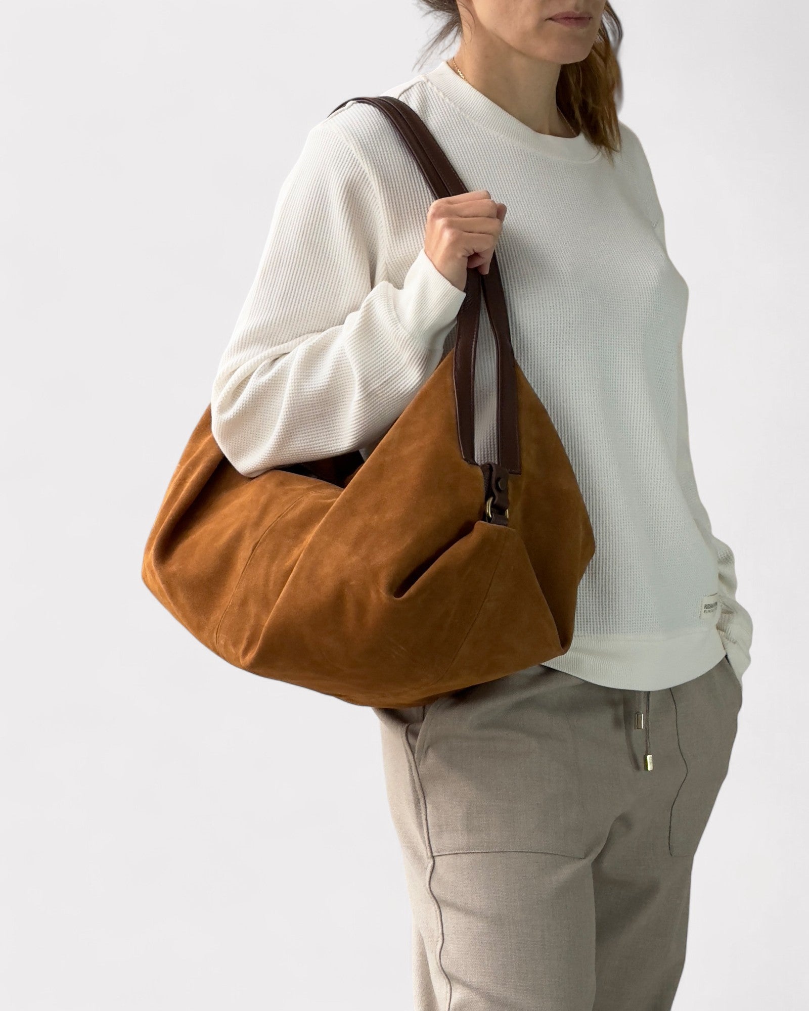 Person holding a tan bag against a white background