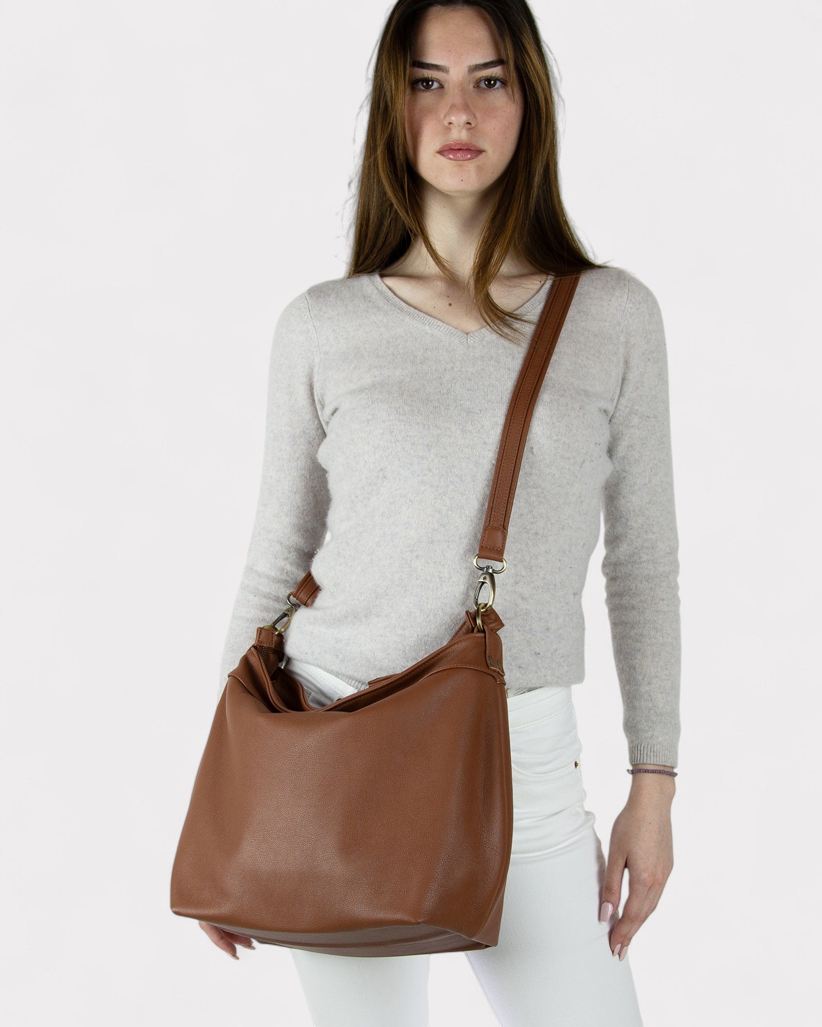 Woman holding a Cognac brown leather bag against a white background