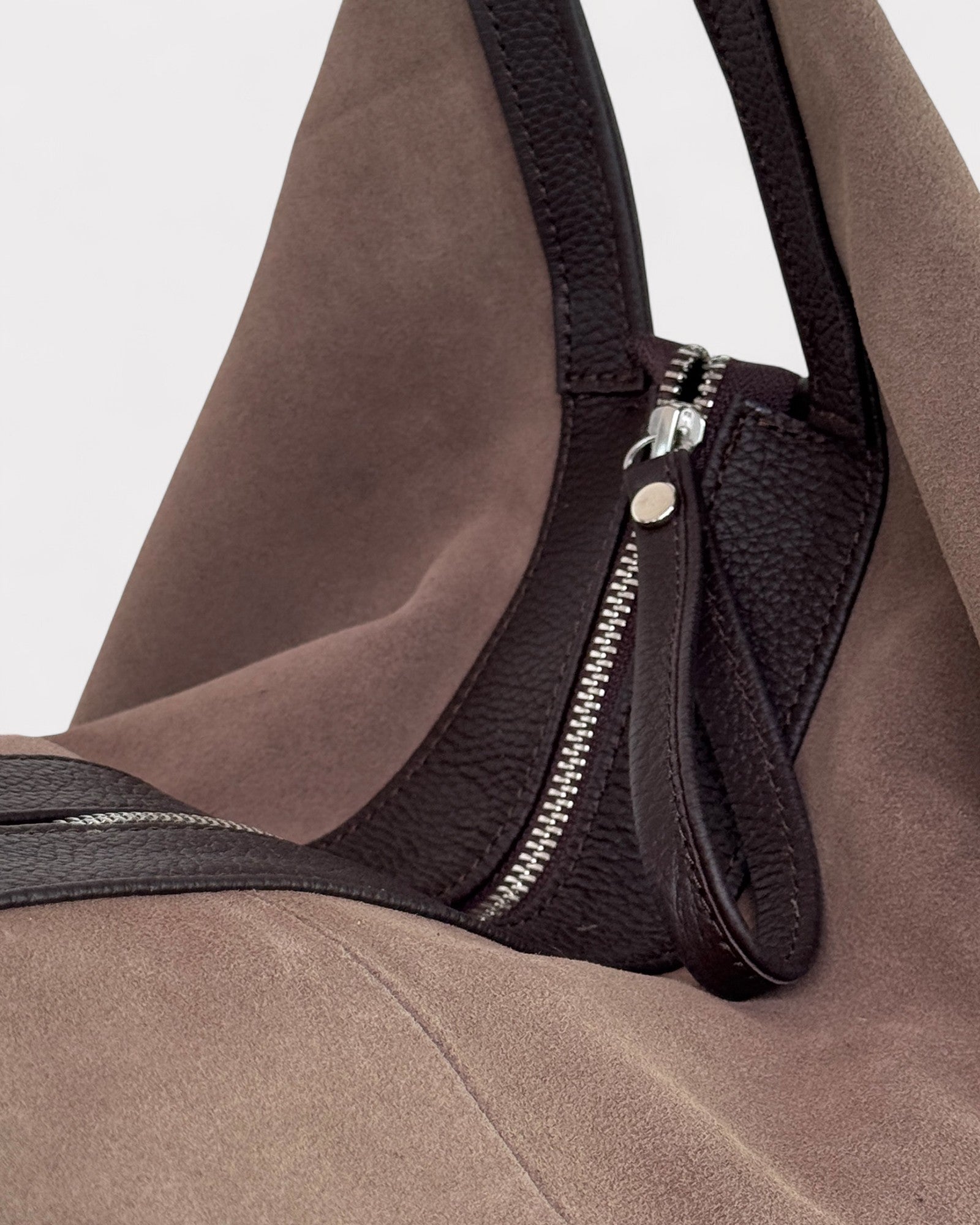 Taupe handbag with a visible zipper on a light gray background