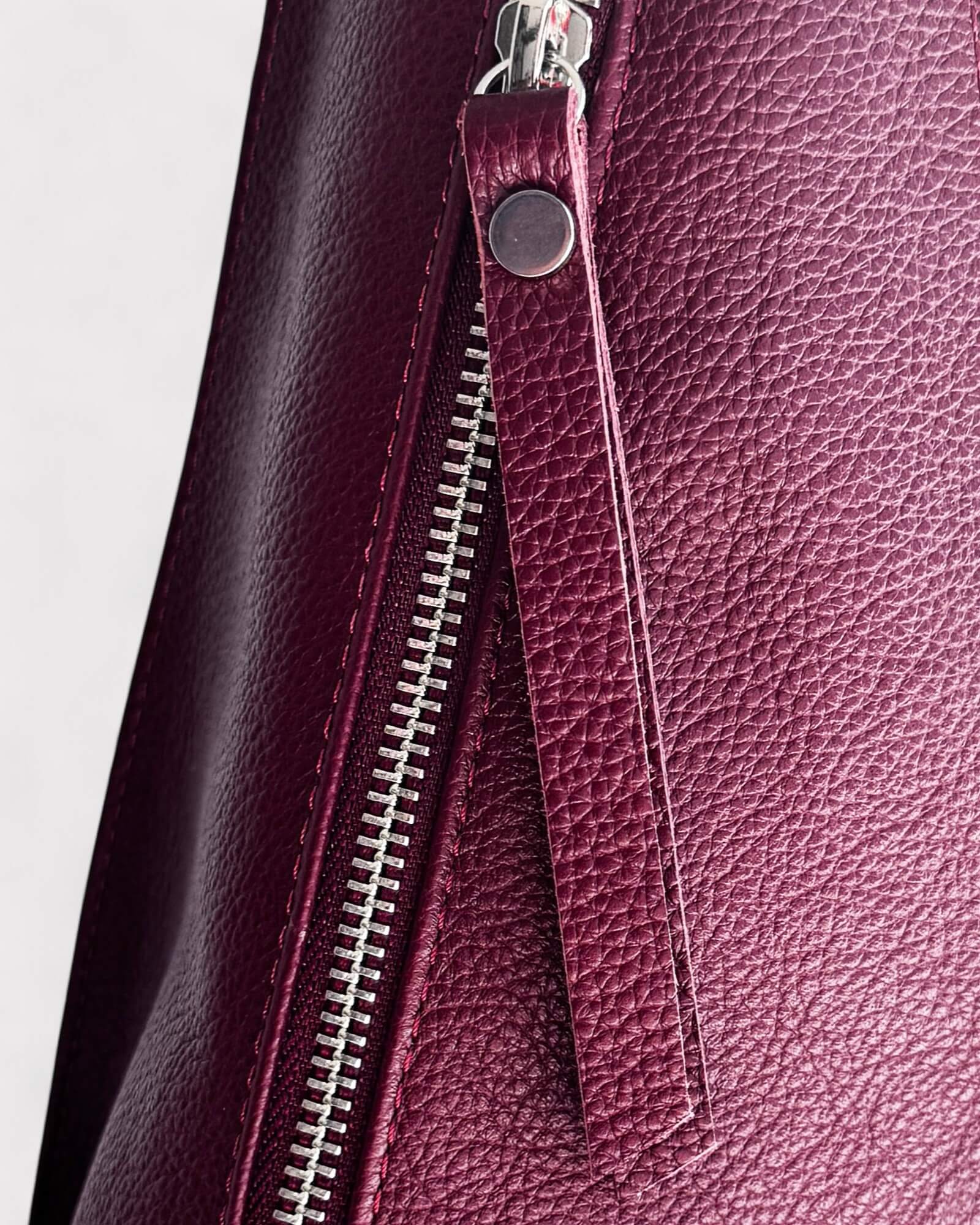Close-up of a purple leather bag with a zipper on a light gray background